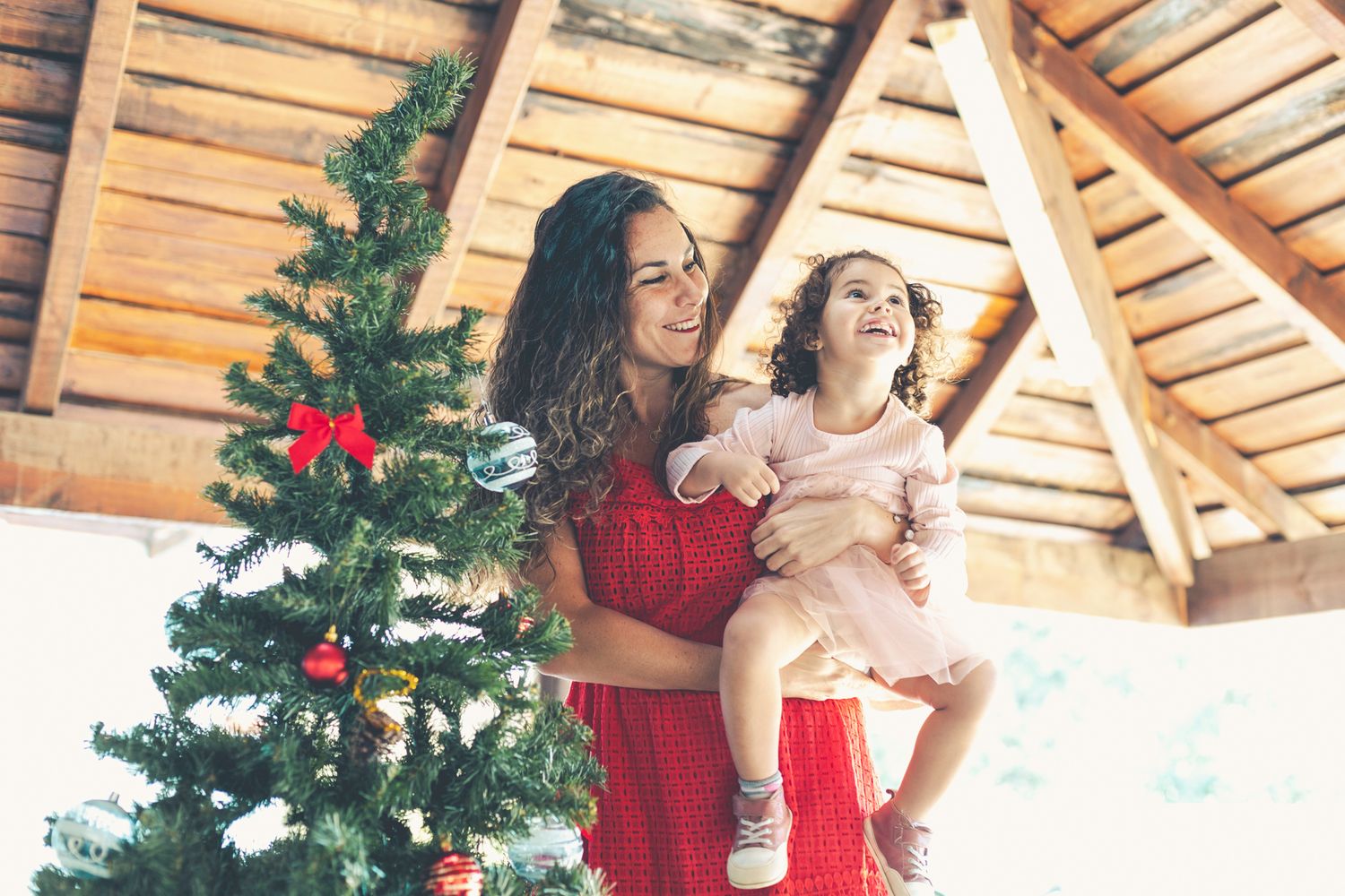 Mamá levanta a Lara para que pueda ver la parte superior del árbol de Navidad.