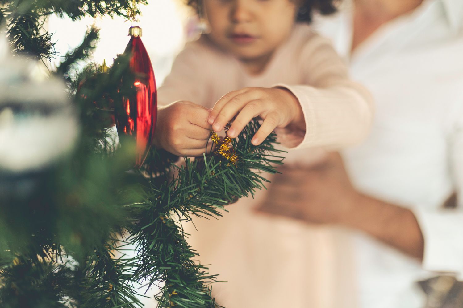 Close-up of a toddler's hand decorating a Christmas tree during a photo session