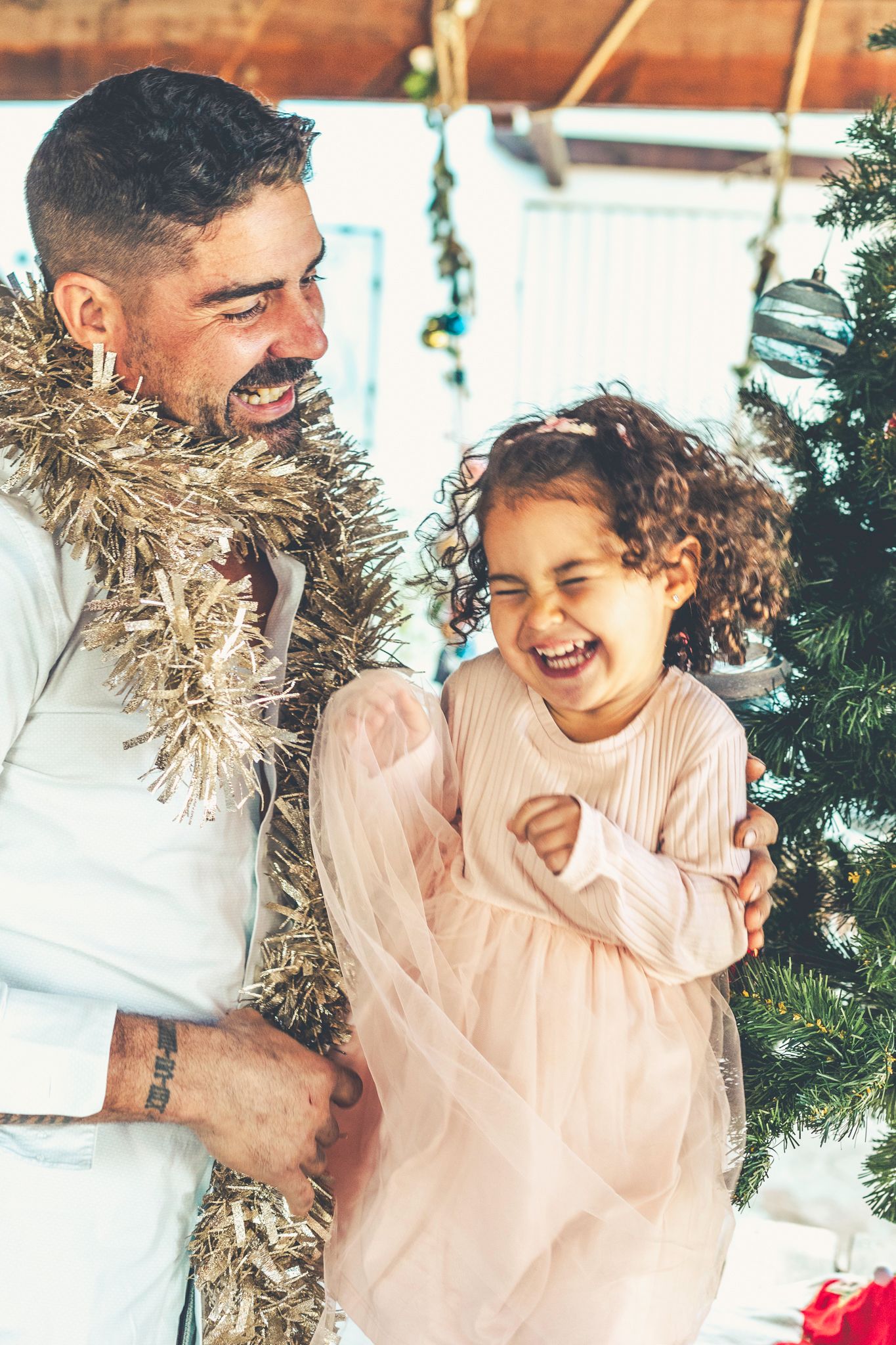 Lara y su padre riendo juntos durante una sesión de fotos navideña