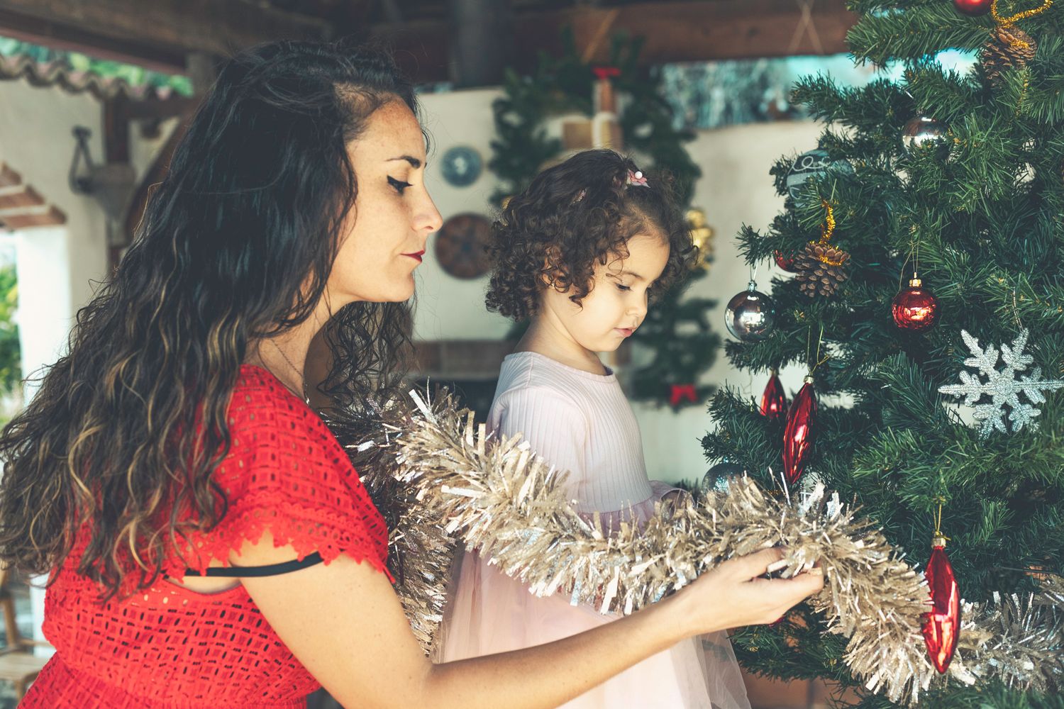 Mummy and Lara are decorating the Christmas tree with silver-colored tinsel.