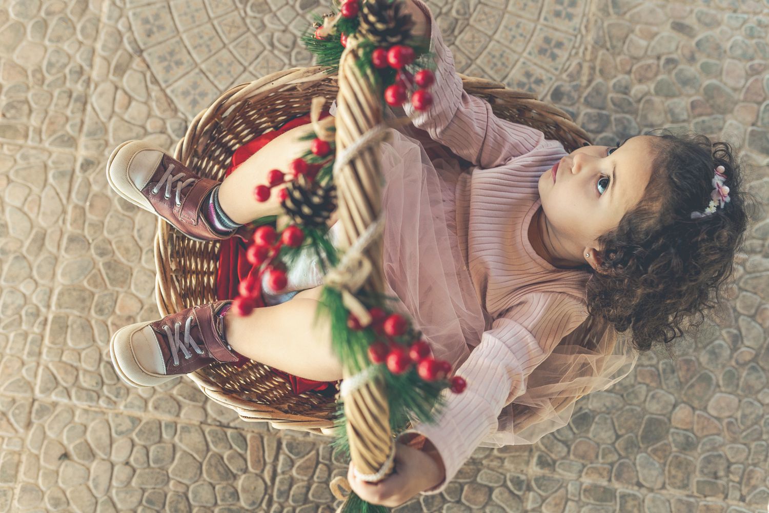 "Toddler girl, Laura, sitting inside a basket decorated for Christmas.