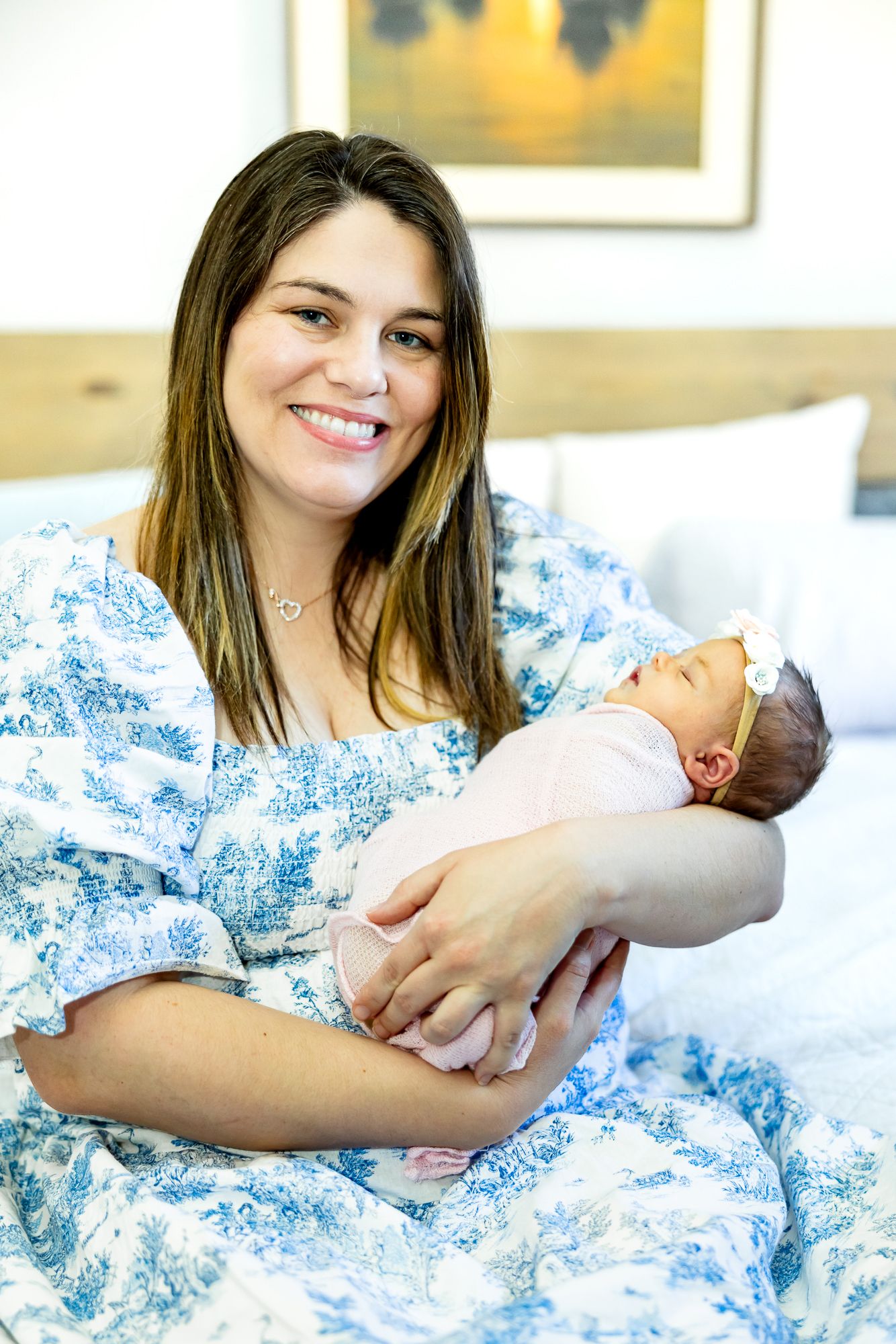 Mom sits holding her new baby girl and smiles during lifestyle newborn photos in Colorado Springs.