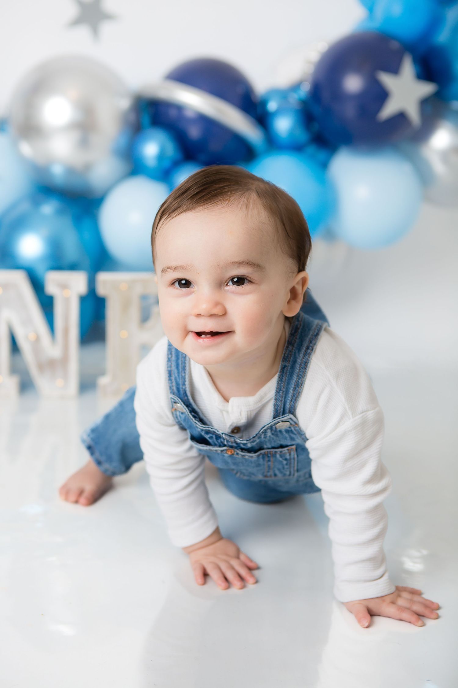 Baby milestone photo with blue and silver balloon arch decoration.