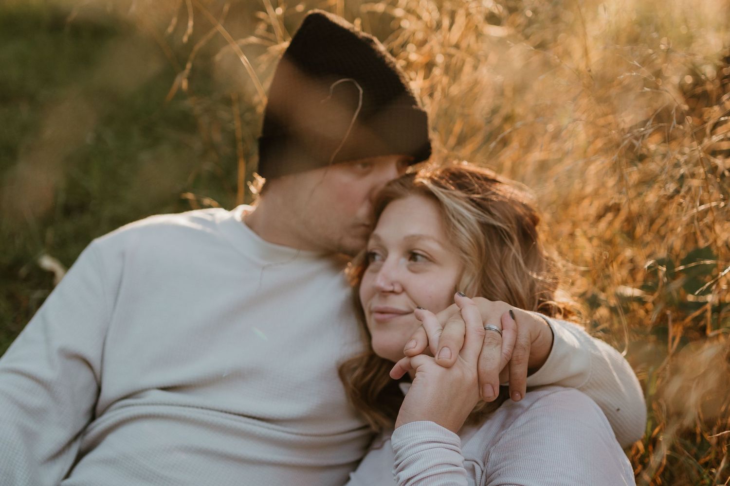 Intimate couple portrait in golden sunlight against natural outdoor backdrop.