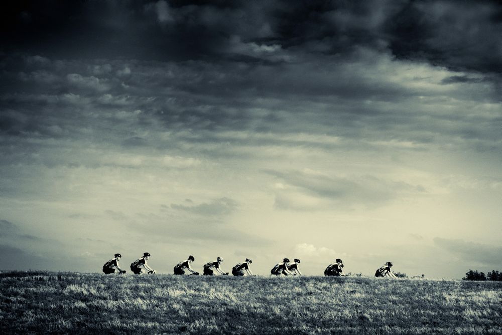 A group of cyclists half hidden behind the dike