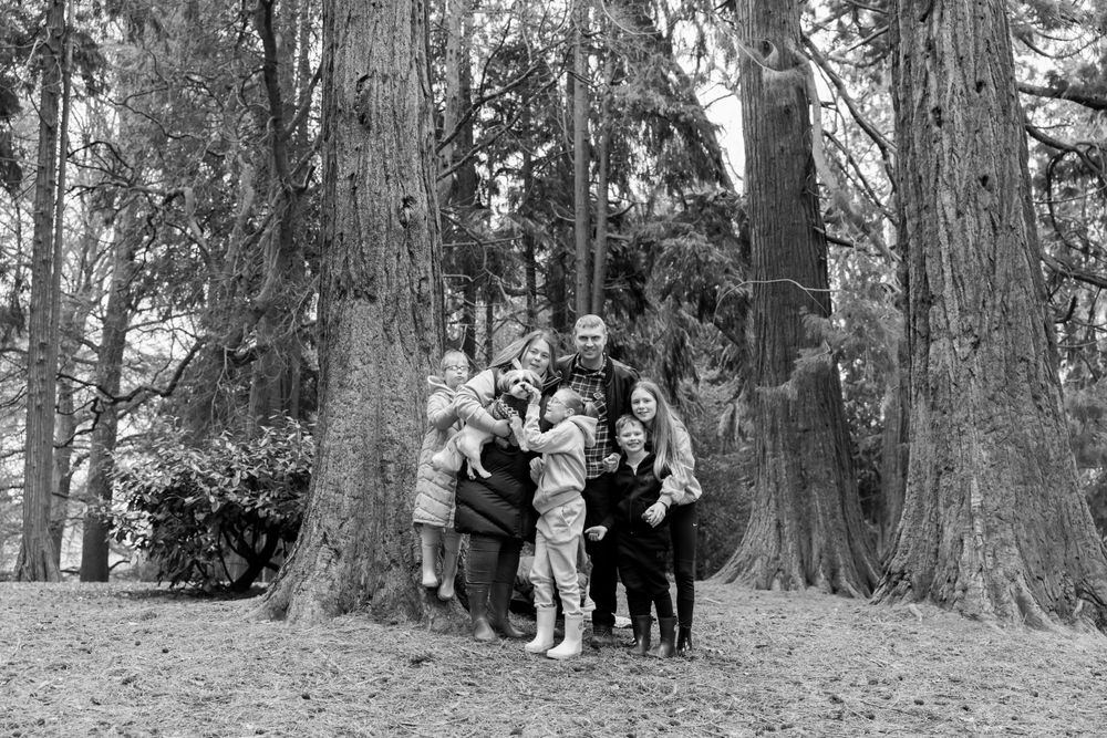 black and white photograph of family of six and dog in woodlands