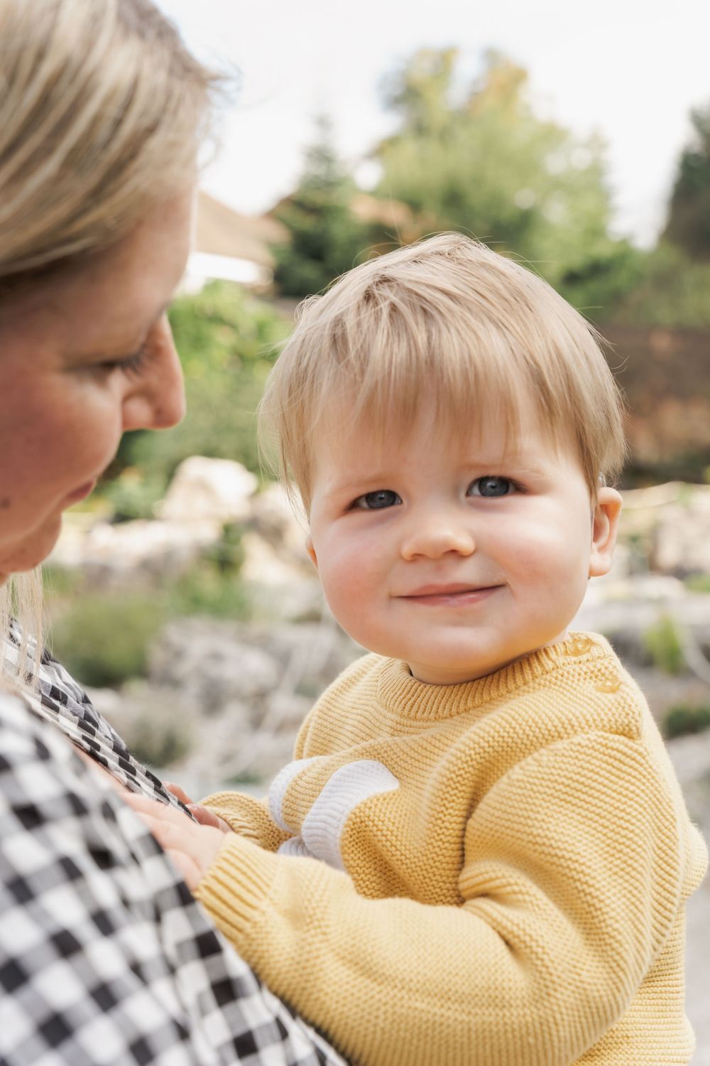 photograph of small boy with hearing aid smiling at camera