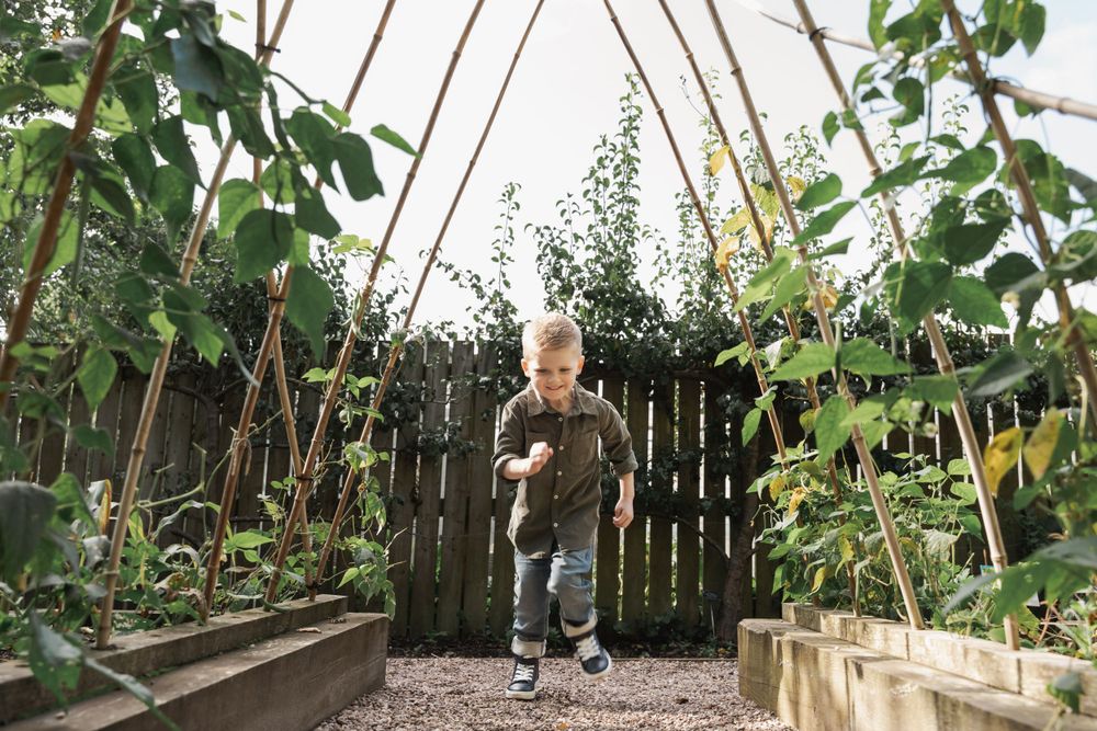 photograph of boy running through arch in garden