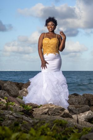 Stunning bridal portrait on rocky beach wearing white and gold mermaid gown.