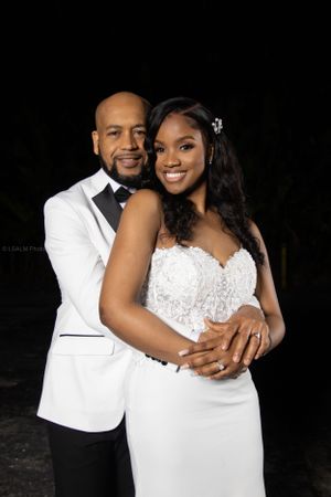 Elegant formal portrait in white attire against dark background.