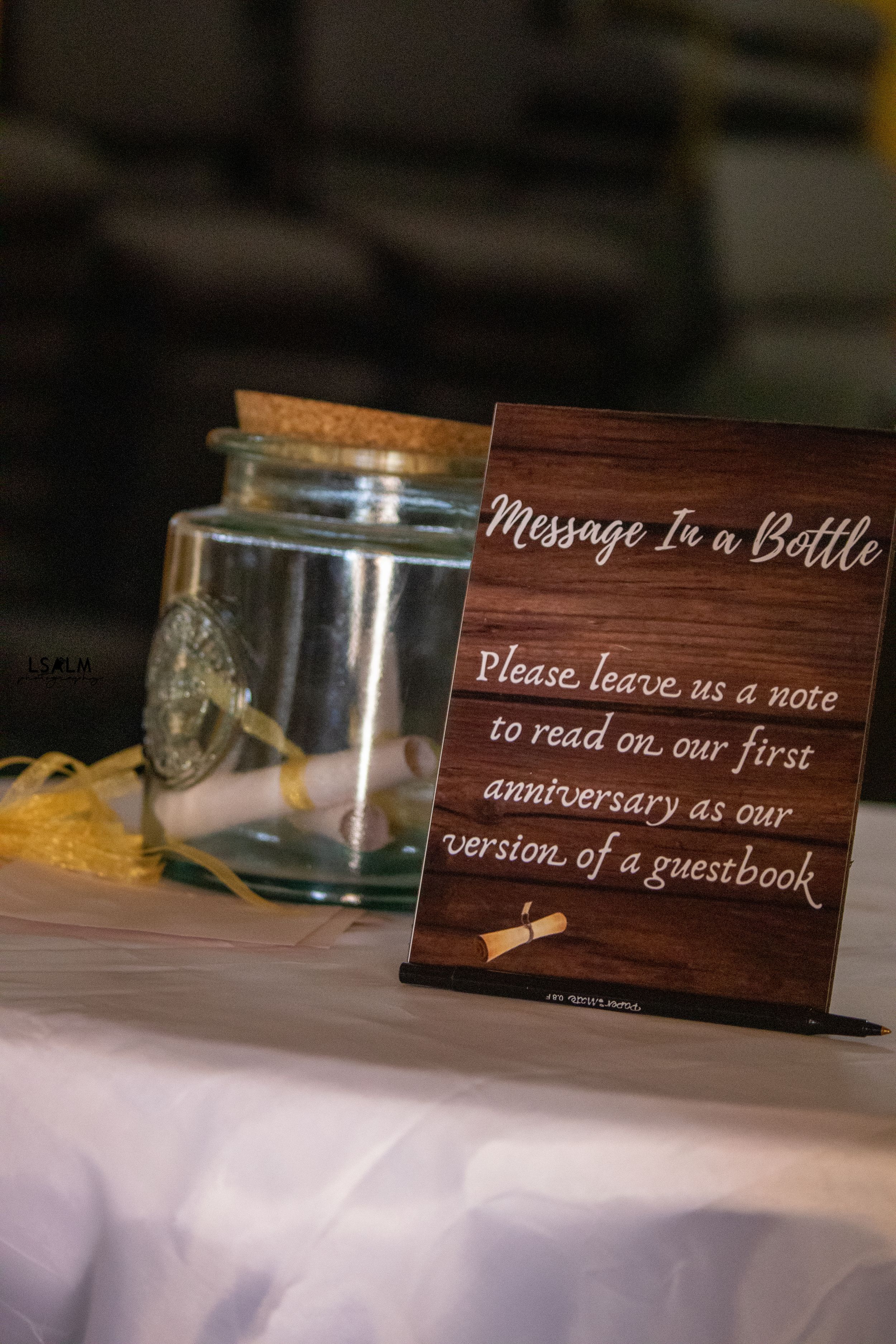 Message in a bottle wedding guestbook sign with wooden decor and glass jar.