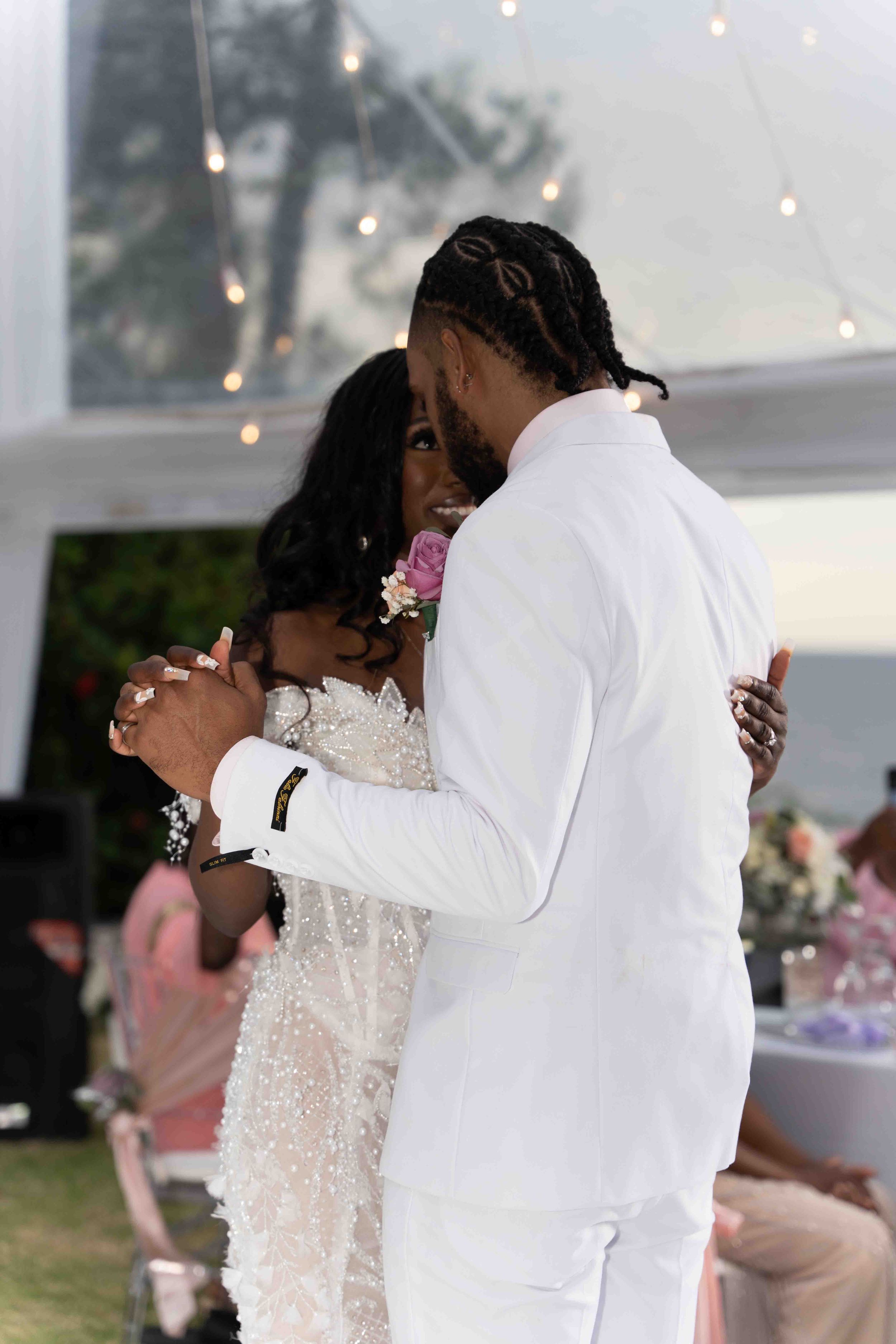 A couple shares an intimate dance moment in elegant white attire at their wedding reception.