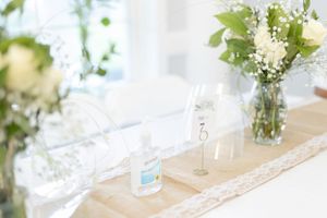 Elegant floral centerpieces with white flowers and greenery decorate tables at an event.