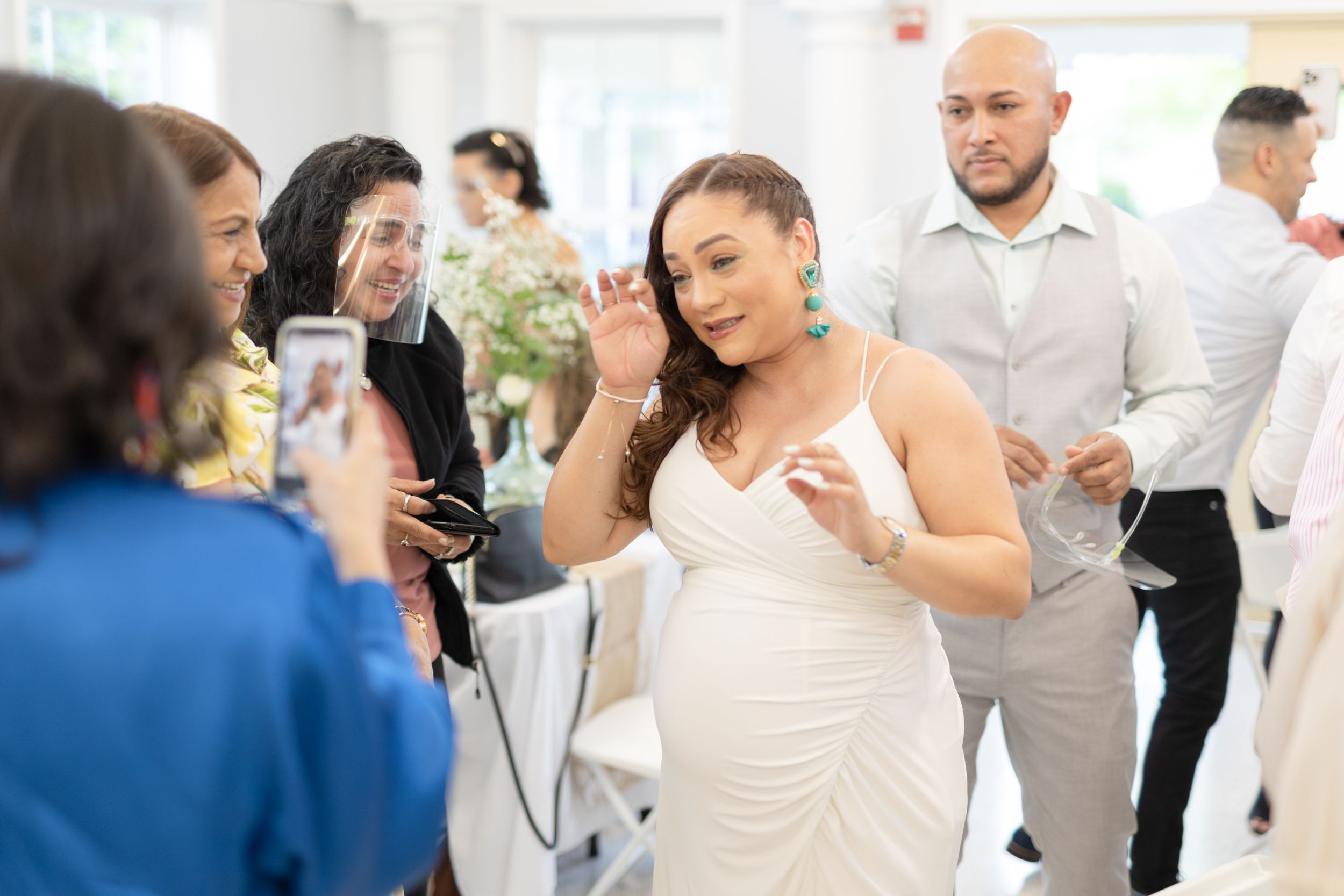 A person in a white dress dances at what appears to be a wedding reception or celebration.