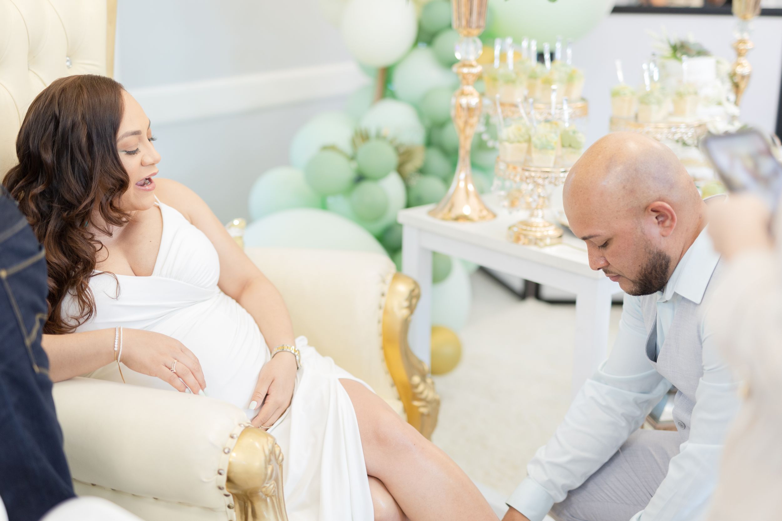 Intimate baby shower celebration with elegant white and gold theme decor.
