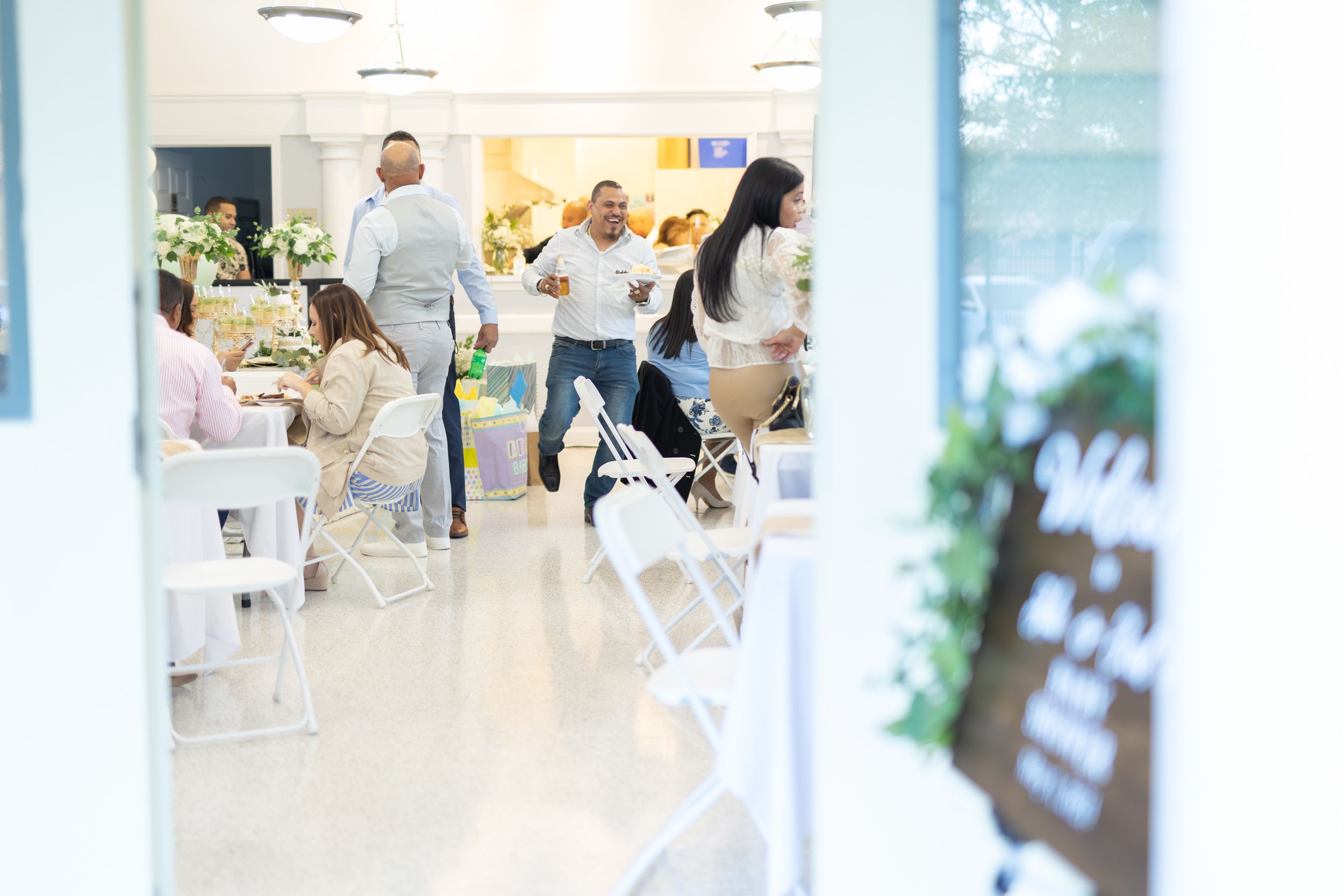 Blurred view through doorway of lively party scene with white decor.