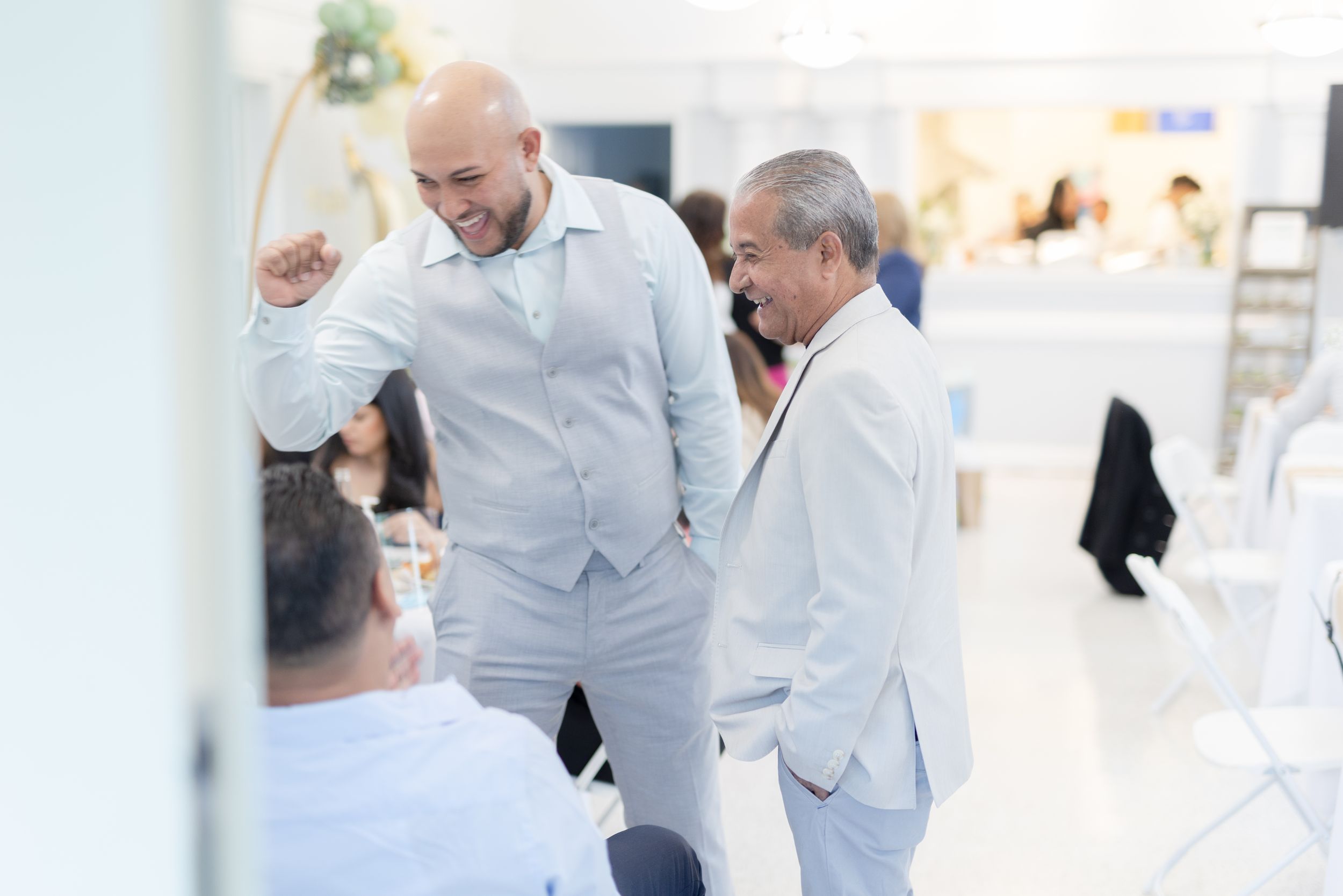 Elegant social gathering with guests in formal white attire mingling indoors.
