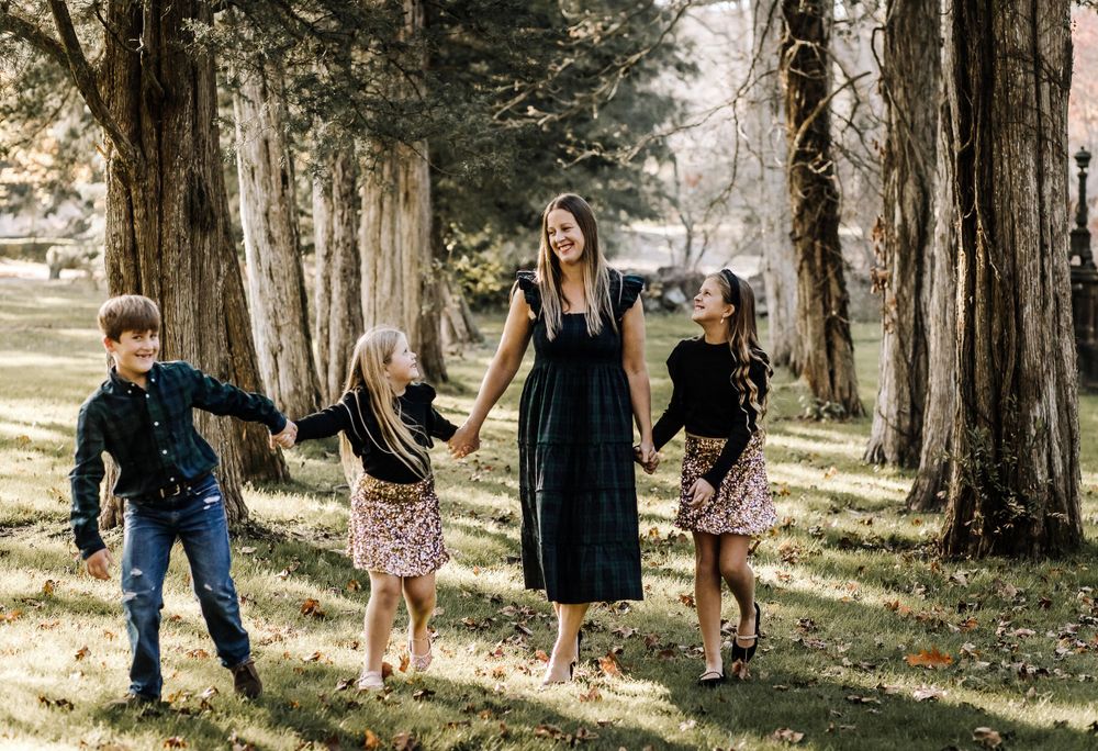 A group walks together on a path through tall trees in a scenic outdoor setting during autumn.