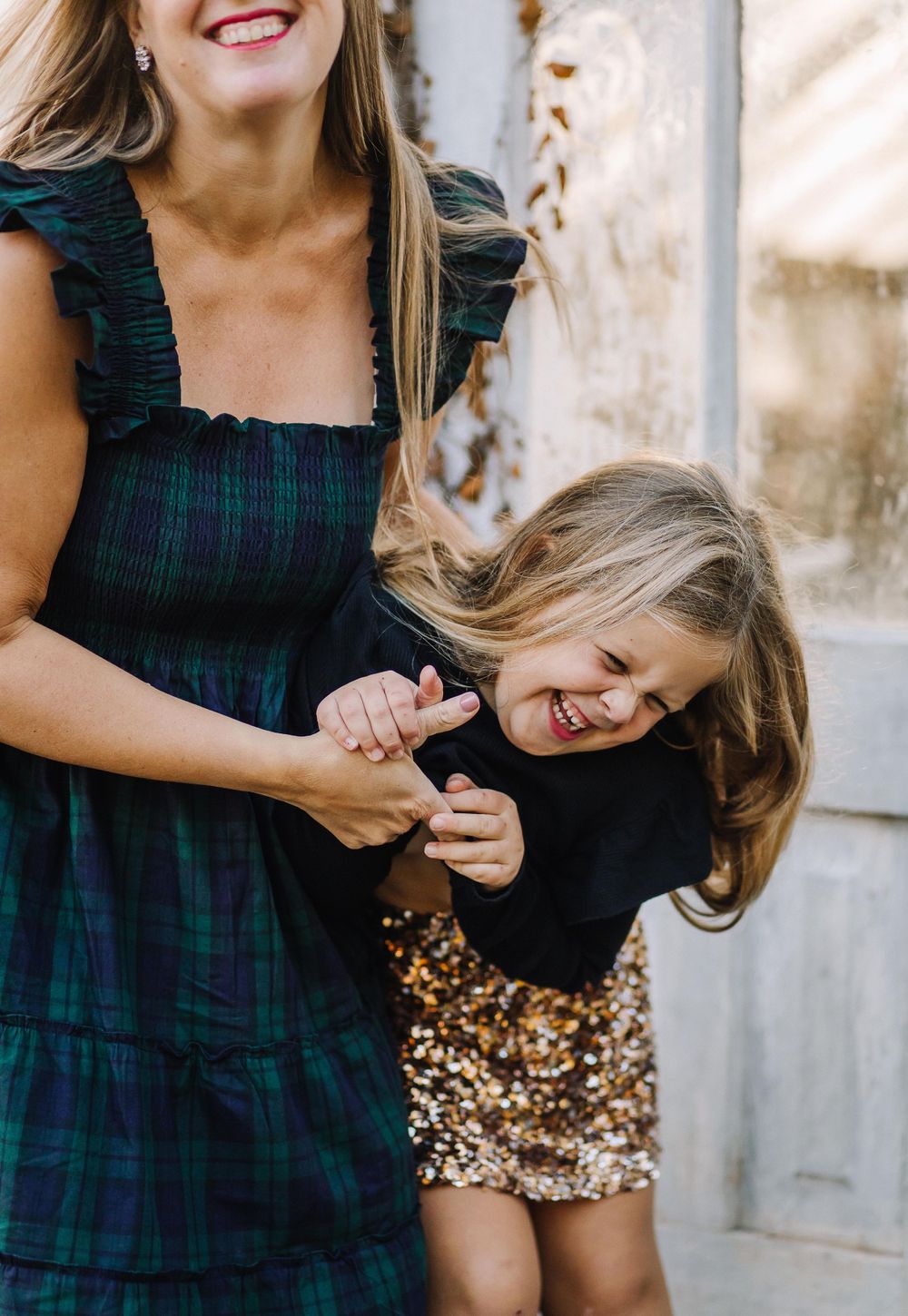 Two people share a joyful candid moment together while wearing dark dresses.