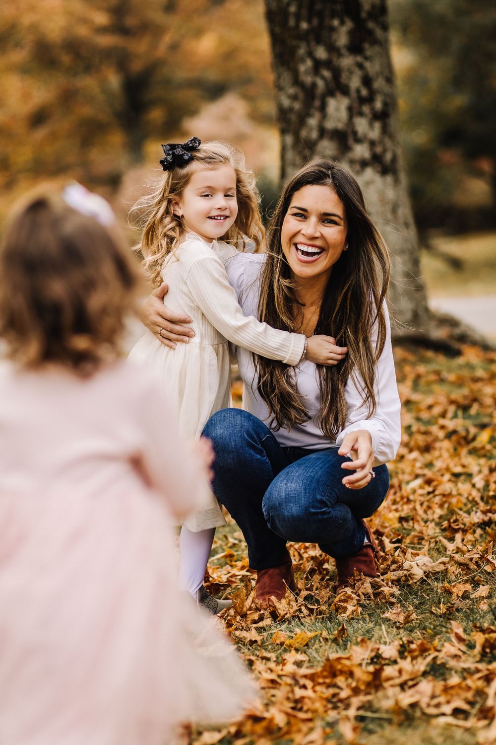 Joyful family moment captured in autumn with fallen leaves and natural outdoor setting.