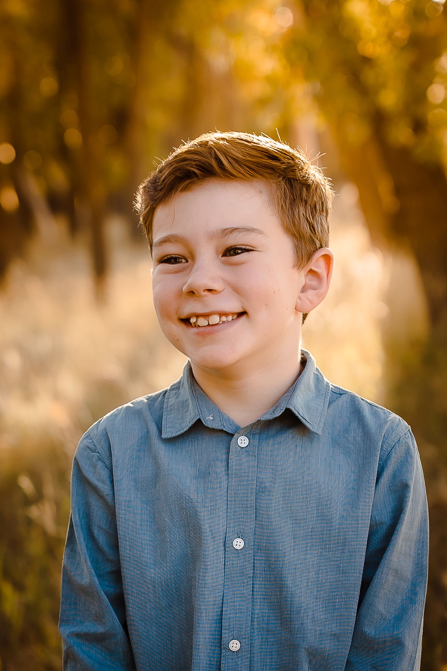 A child smiles broadly in a warmly lit Denver field