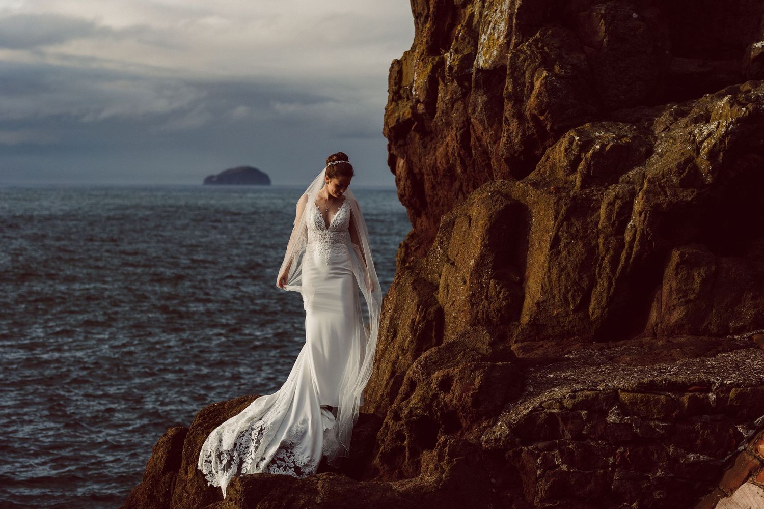 Dramatic wedding photography on rugged ocean cliffs under moody sky.