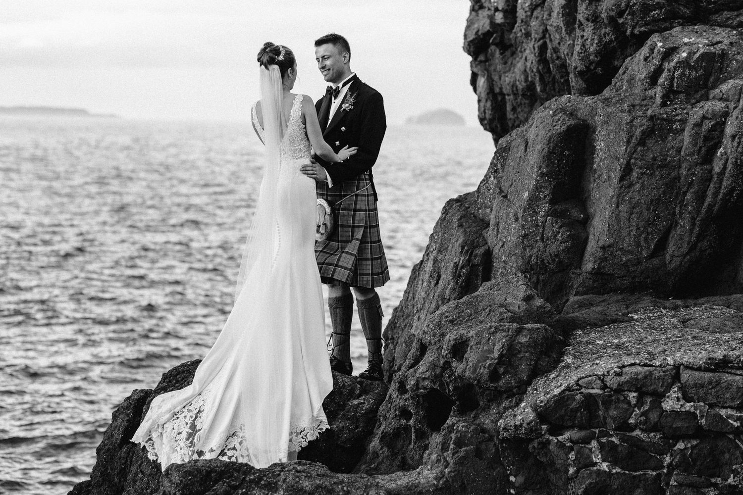 Black and white wedding photography on dramatic coastal cliffs by the sea.