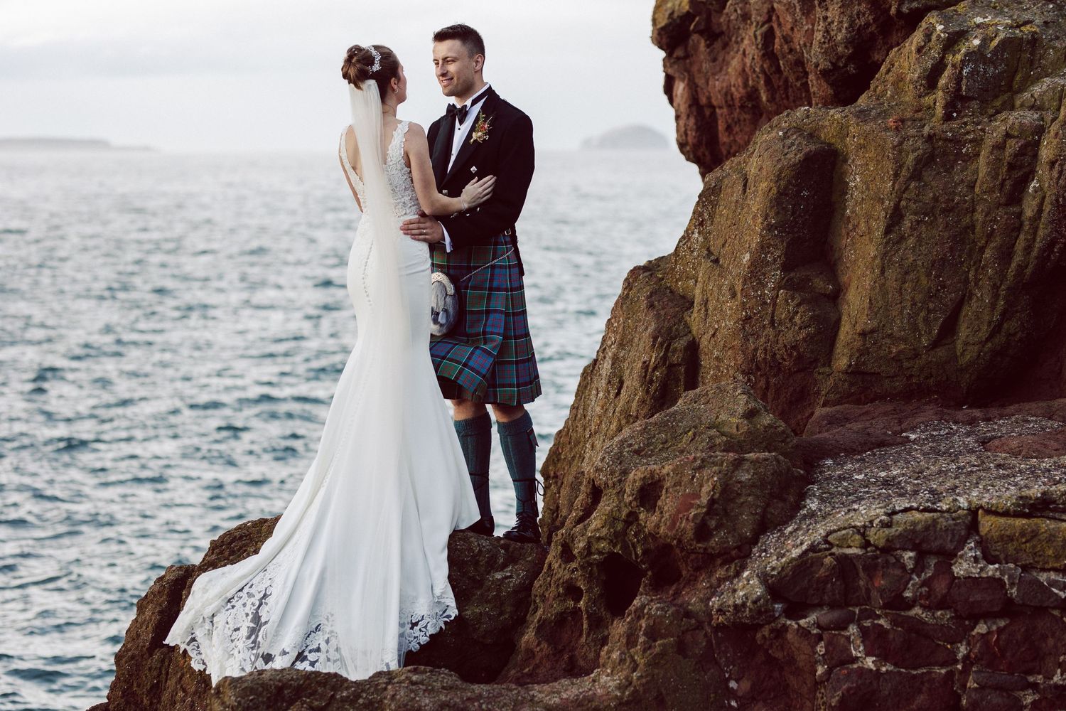 Romantic coastal wedding photography session with dramatic ocean cliffs and waves.