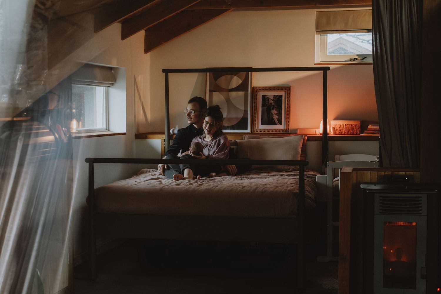 Couple sitting together on a bed in a warmly lit cozy bedroom retreat.