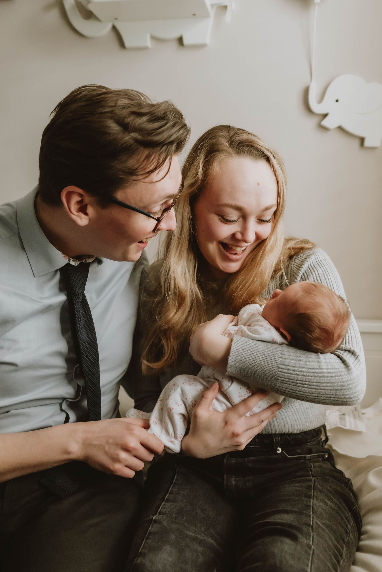 An intimate family moment shows new parents cuddling their newborn baby beneath paper wall decorations.