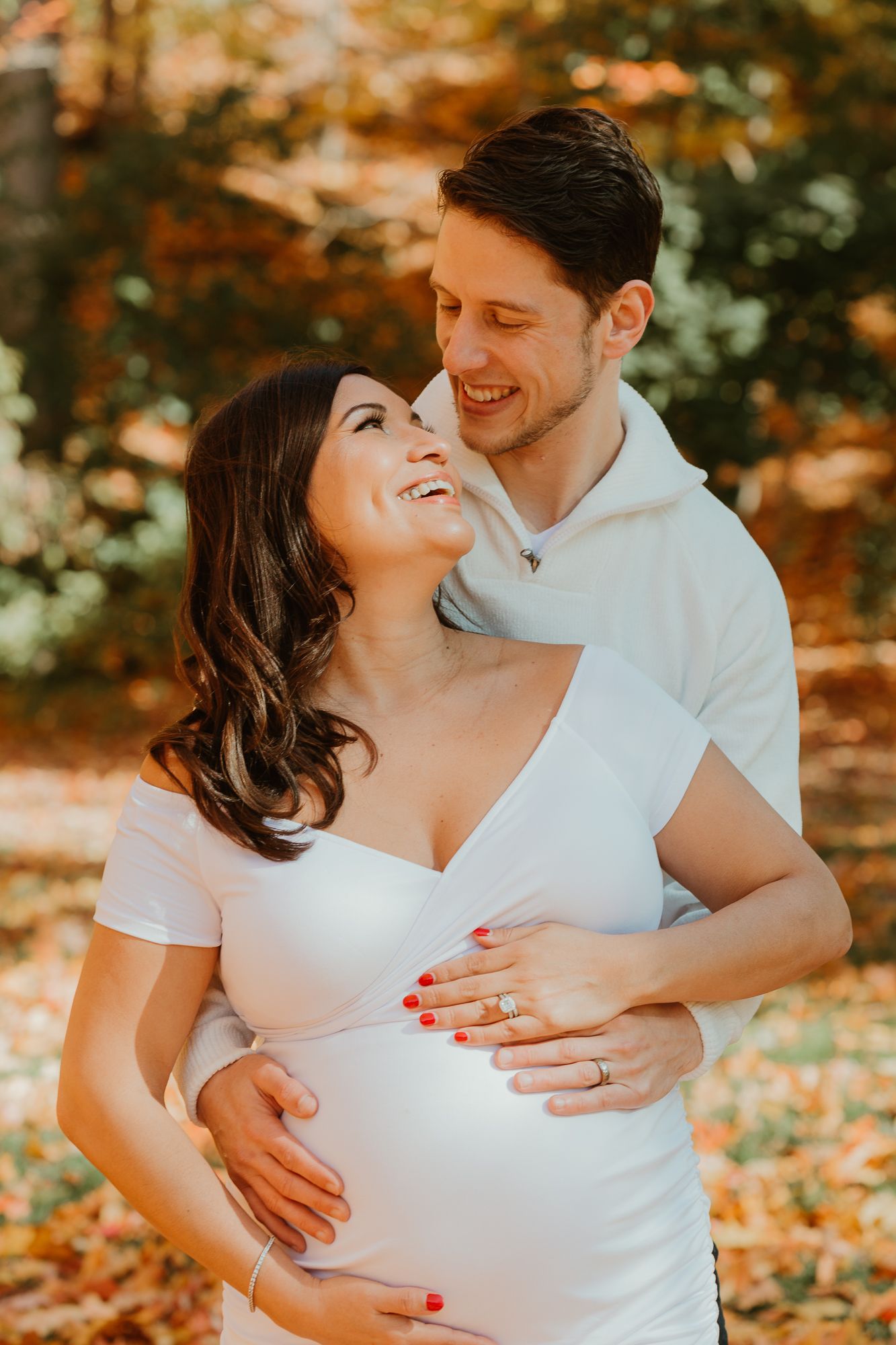 Maternity photoshoot with couple in white outfits during autumn season.