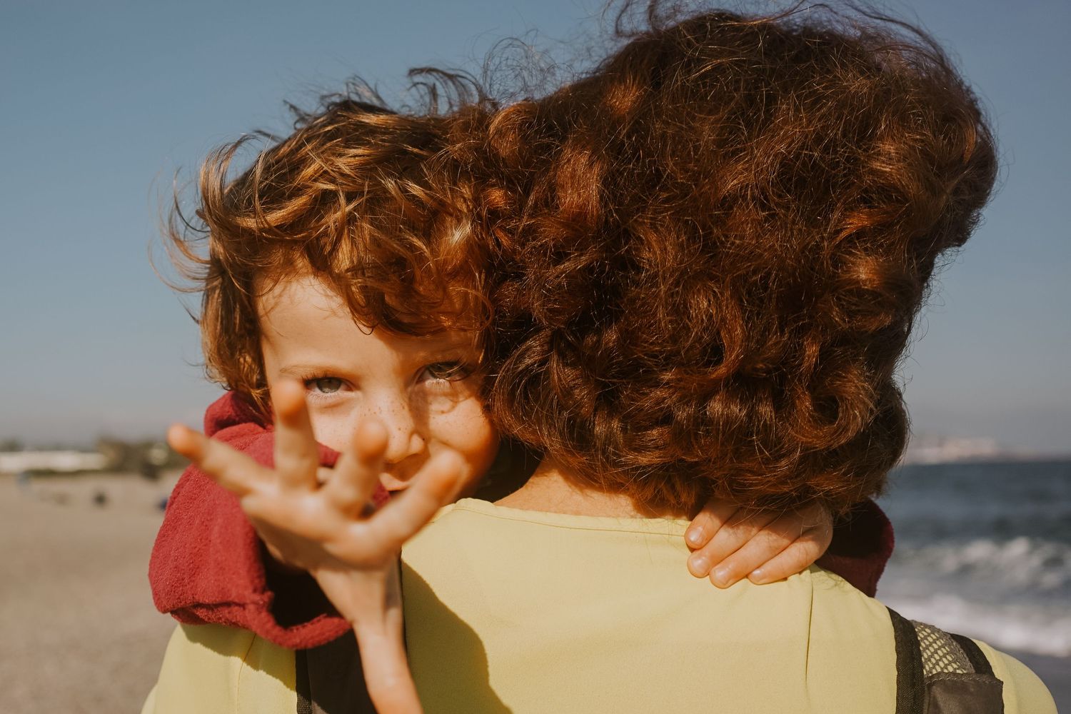 Child with mother outstretching hand to camera on the beach at Sotogrande