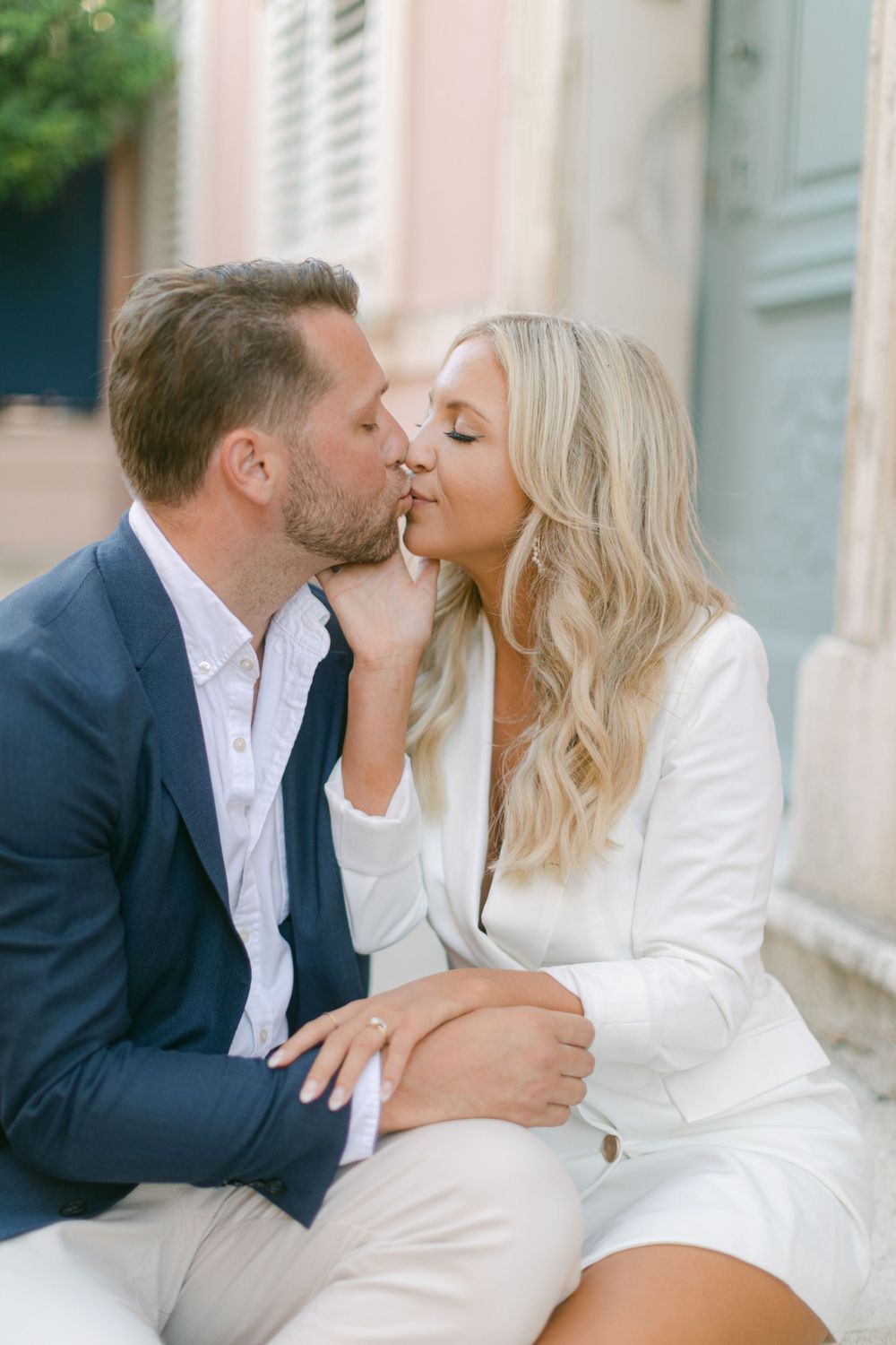 Un baiser romantique échangé entre un couple vêtu d’élégantes tenues de cérémonie.