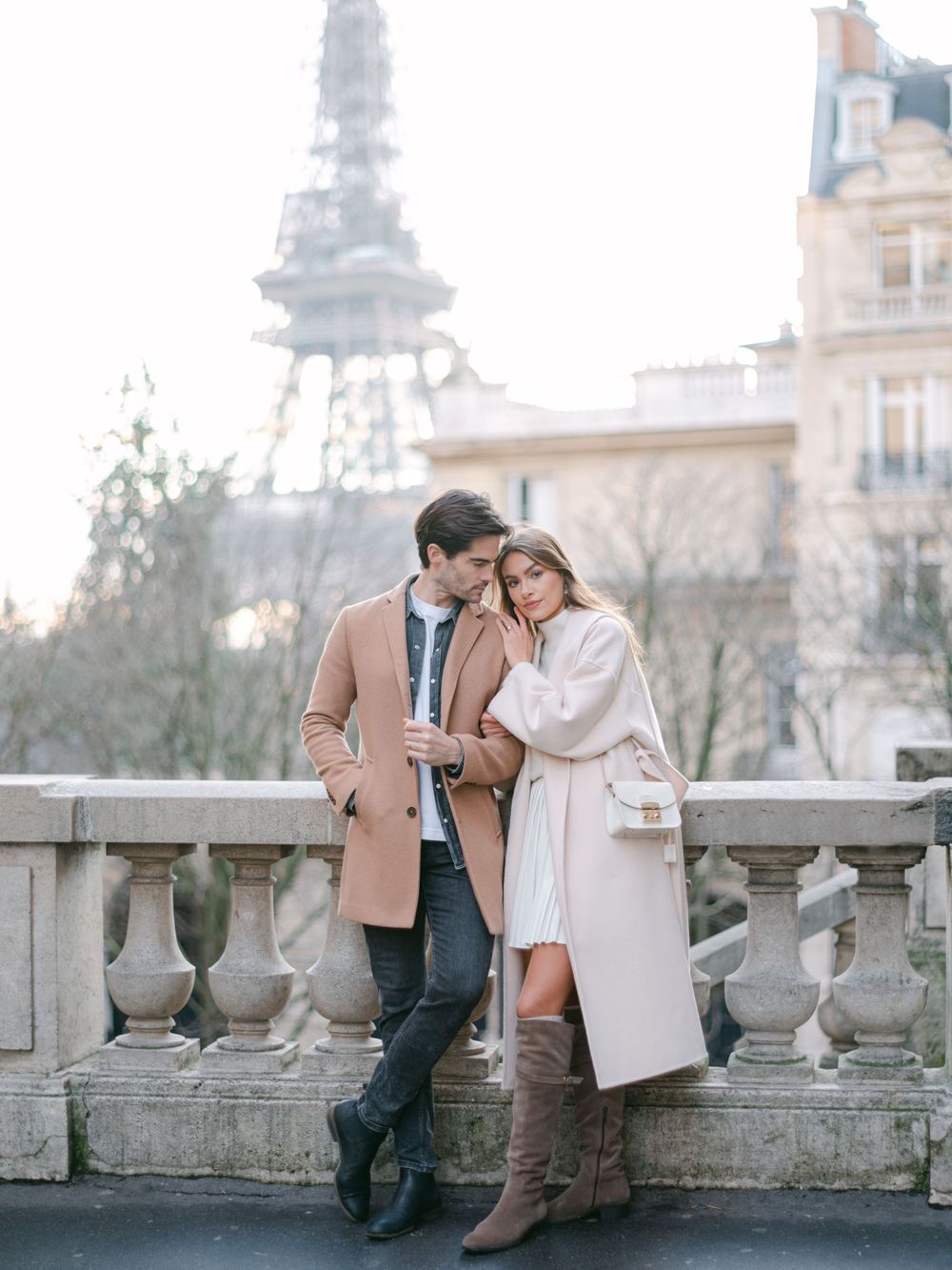 Un couple romantique s’enlaçant sur un balcon parisien avec la Tour Eiffel en arrière-plan.