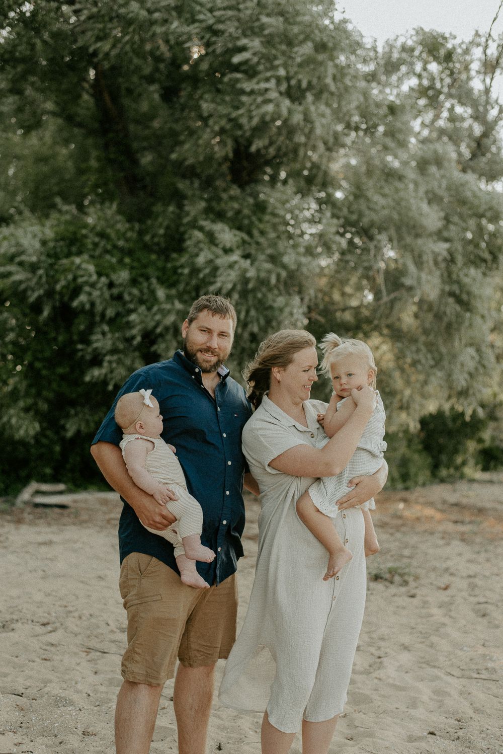 Family portrait of four people standing together outdoors in casual summer attire.