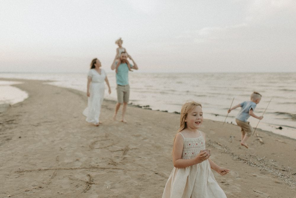 Family enjoying playful moments together on a breezy beach at sunset.