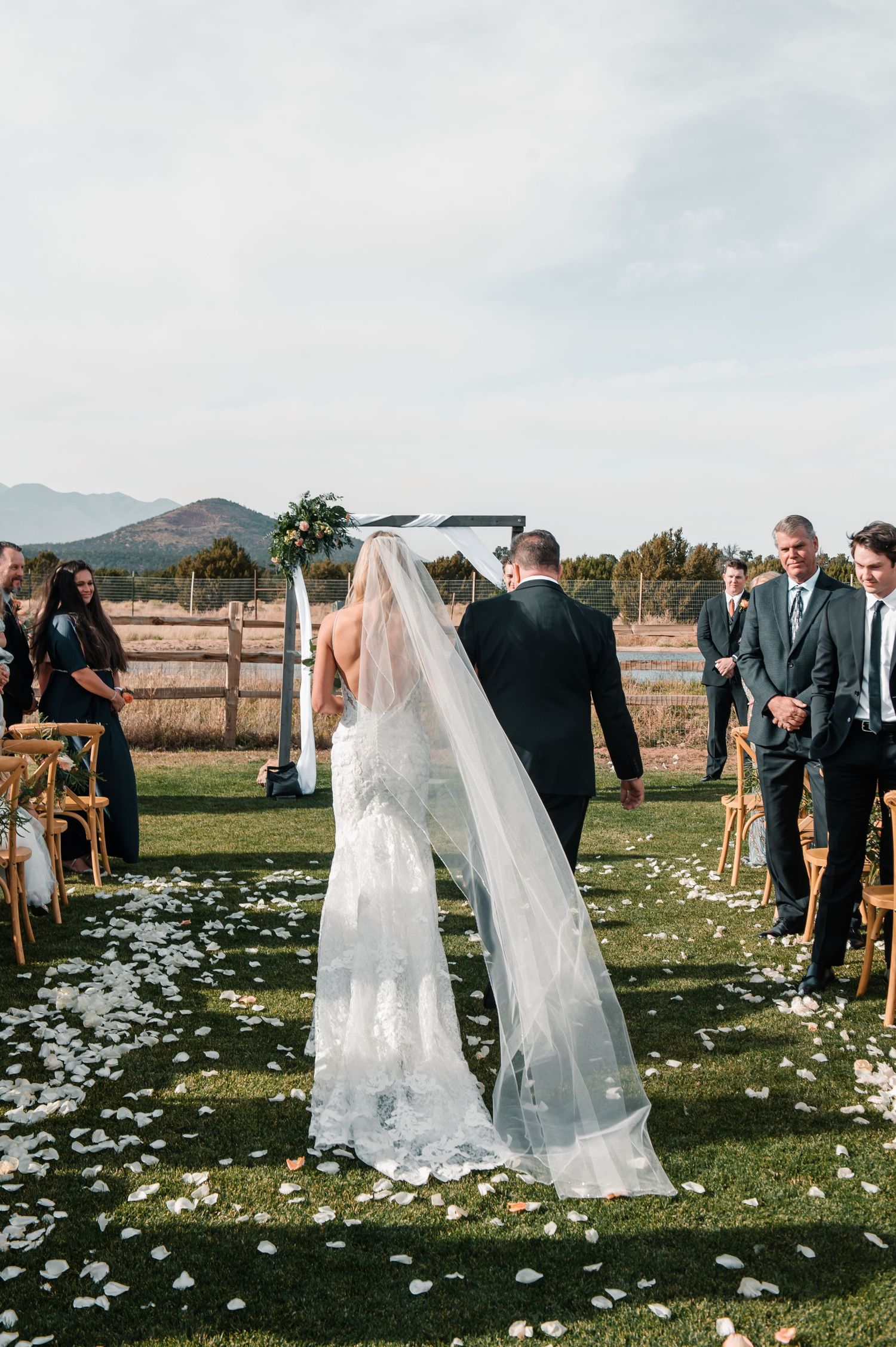 An outdoor wedding ceremony with flower petals scattered on grass.