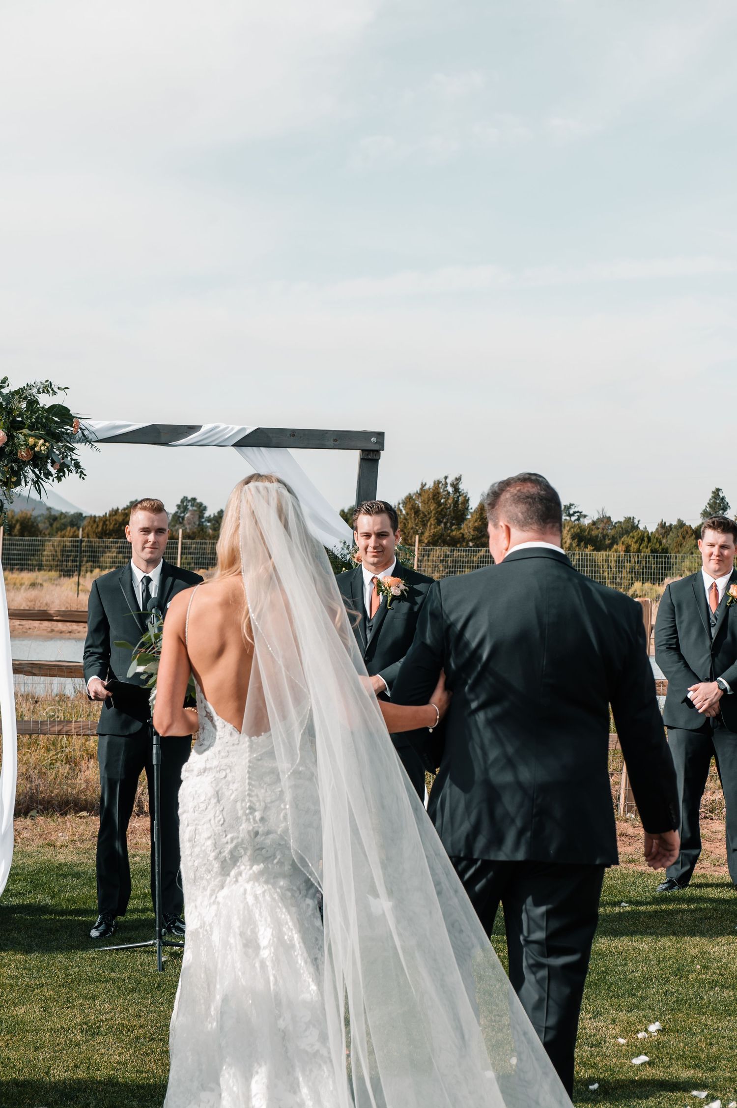 Wedding guests gather on a grassy lawn during an outdoor ceremony.