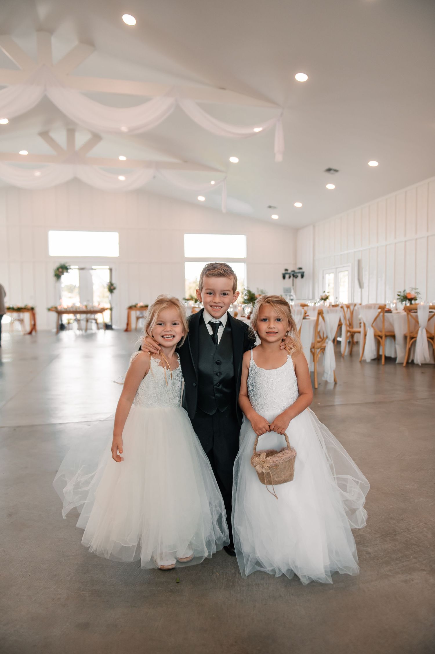 Wedding reception venue interior decorated with white draping and elegant table settings.