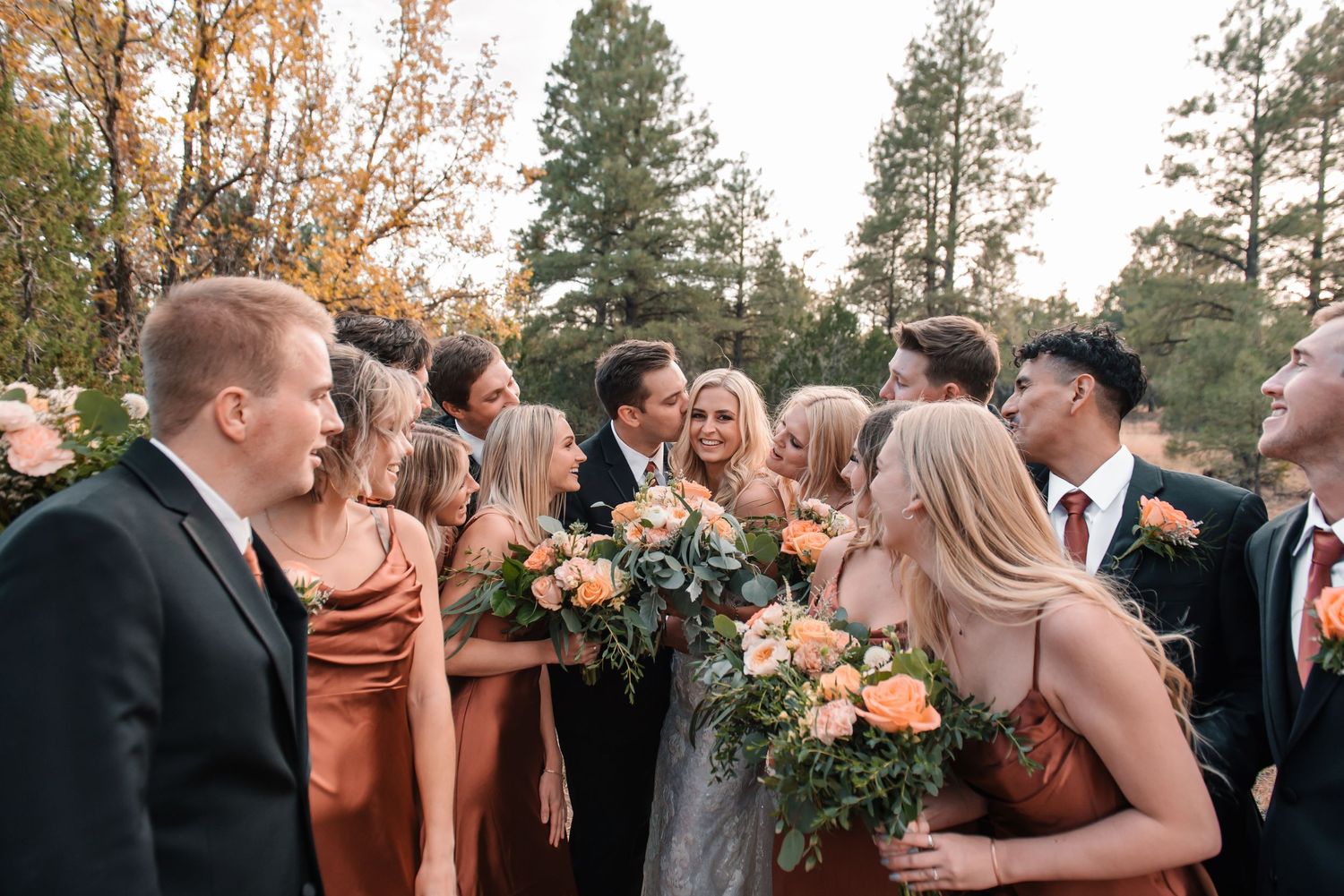 Candid moment of wedding party celebrating and laughing together outdoors.