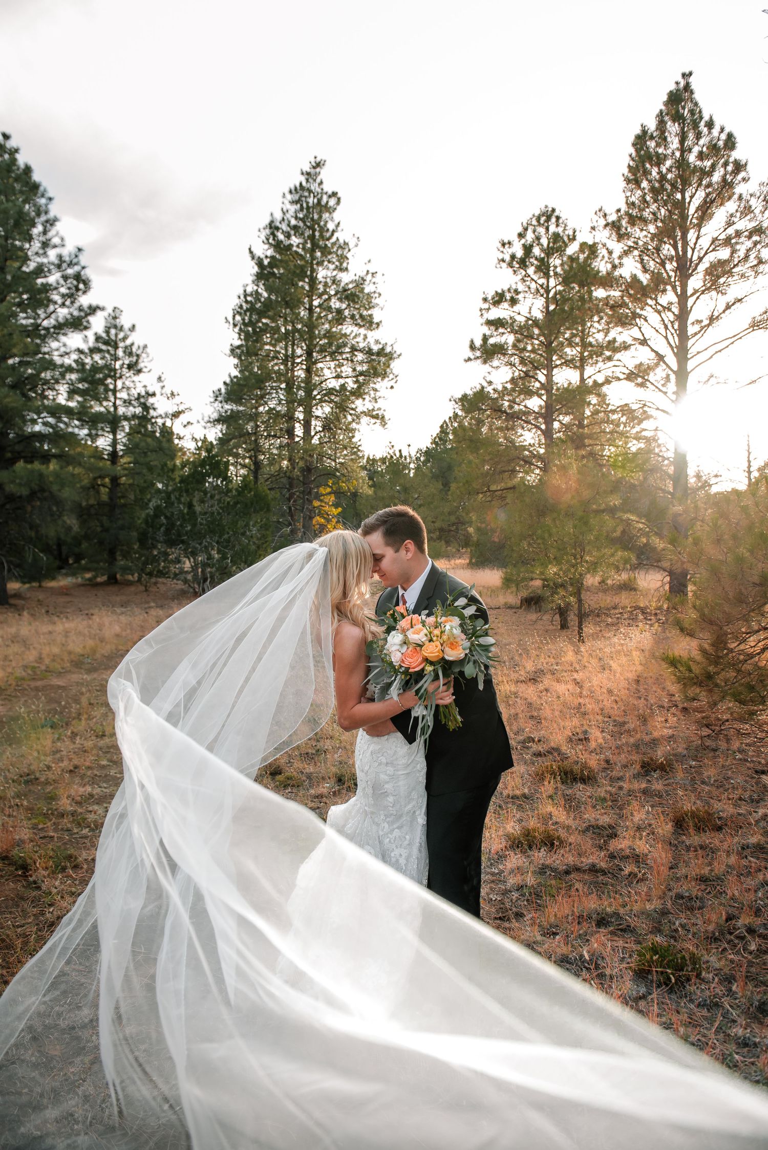 Flowing white wedding veil catches wind dramatically during sunset portrait session.