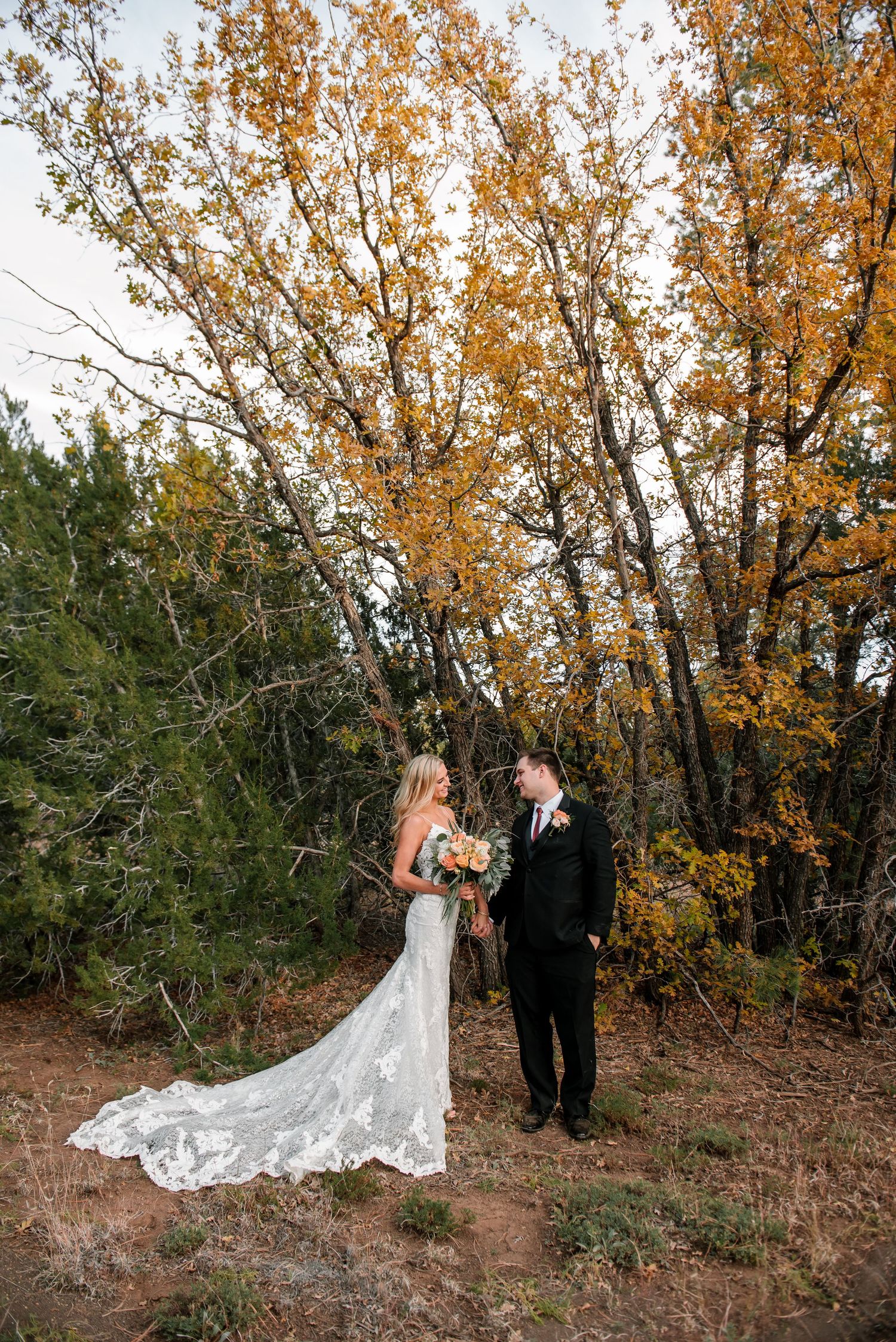 Newlyweds share a romantic moment surrounded by fall foliage.