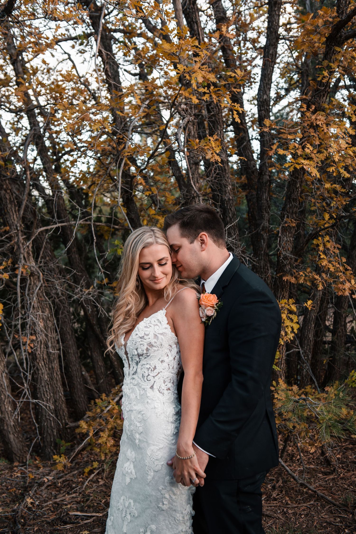 Intimate wedding portrait beneath golden autumn leaves.