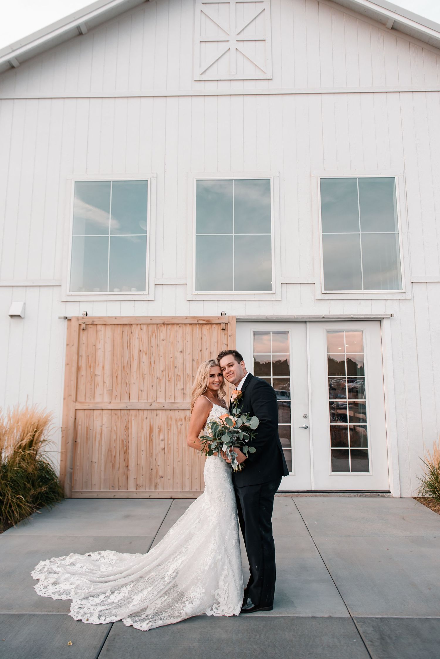 Elegant wedding portraits in front of a modern white barn venue.