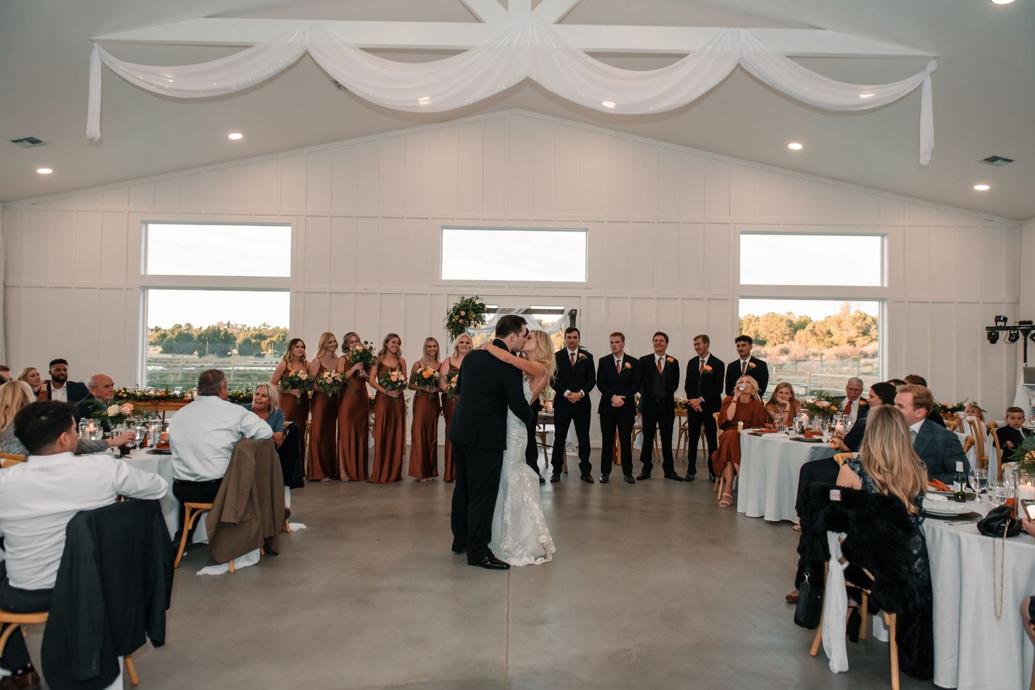 Couples dancing during a first dance at a wedding reception in an elegant white-draped venue.