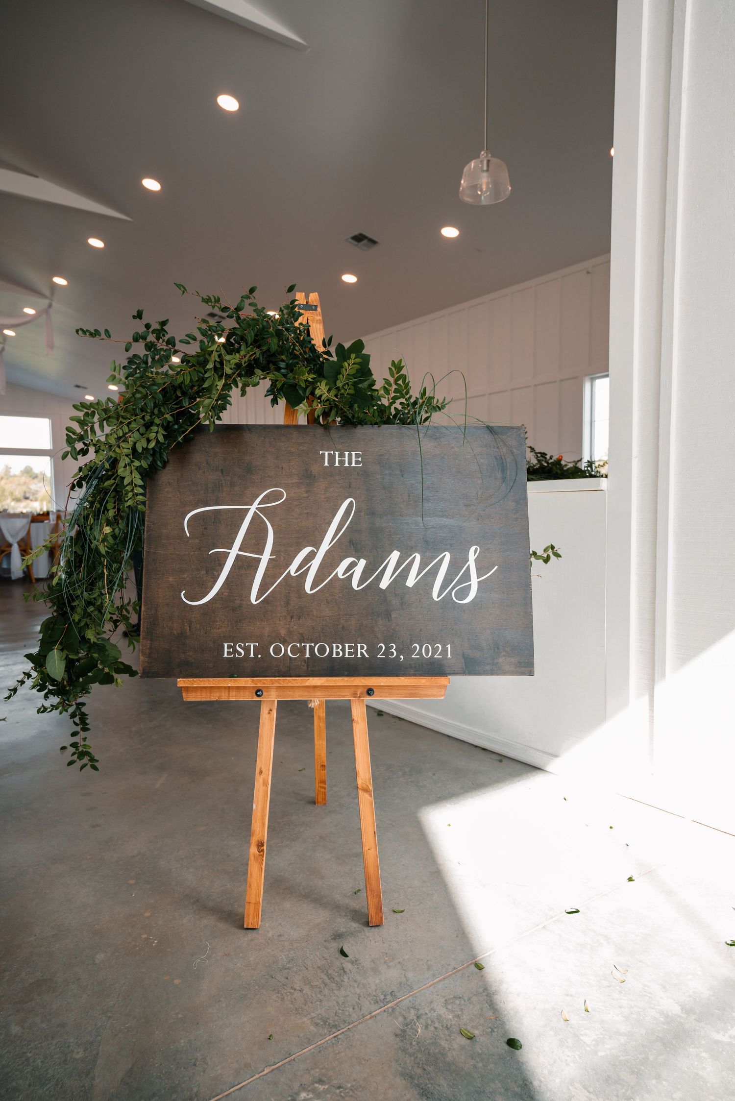 Rustic wooden signs displaying 'The Finns' and wedding date on wooden easels with greenery decorations.