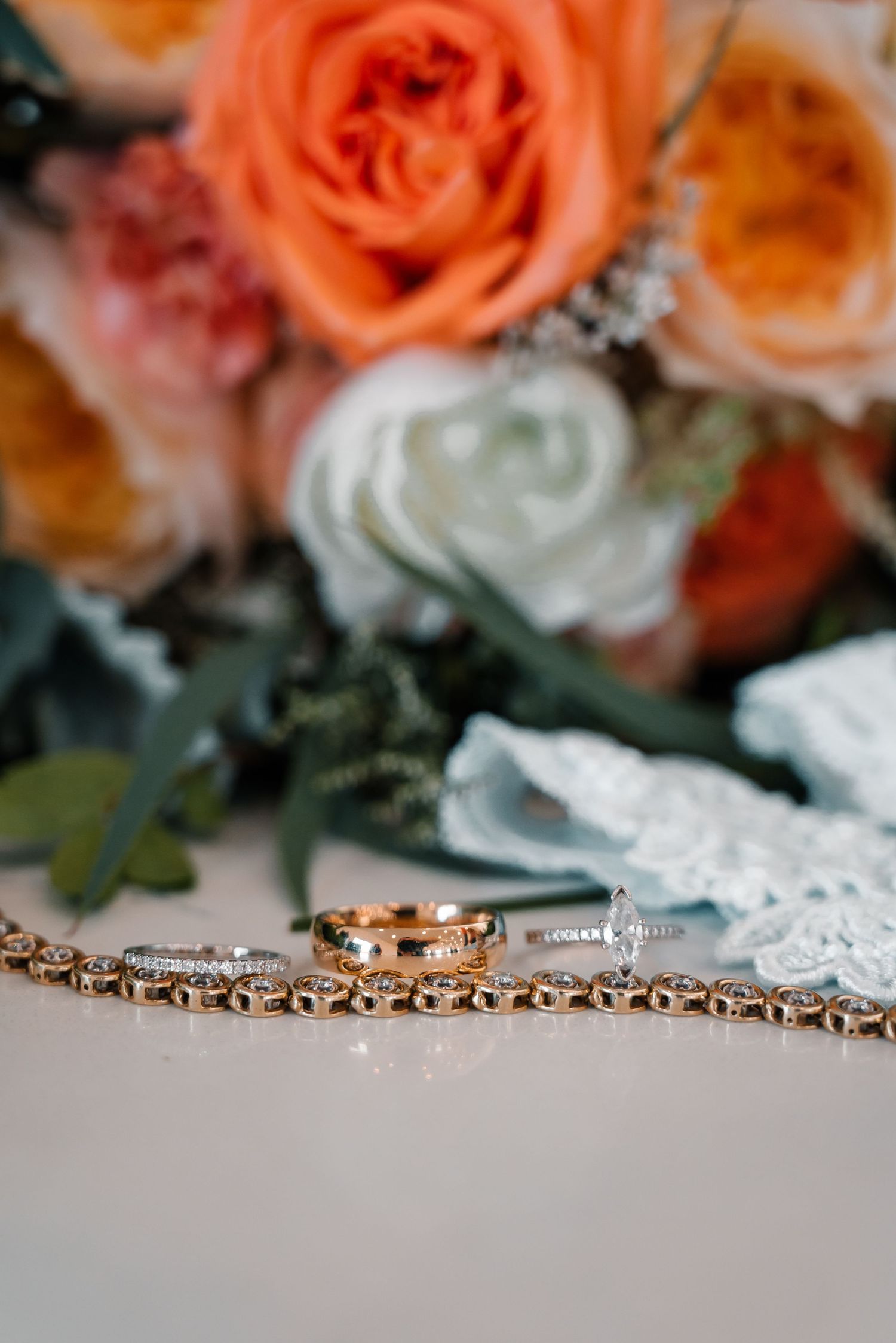 Wedding rings and jewelry displayed with coral roses and lace details.