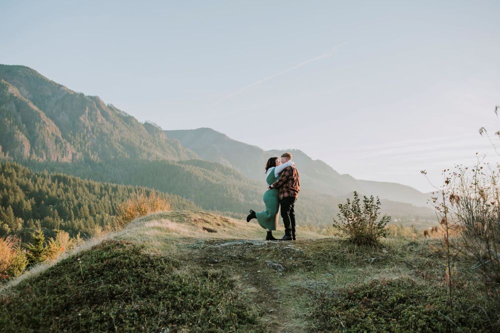couple kissing on top of green hill at sunset in the Columbia River Gorge