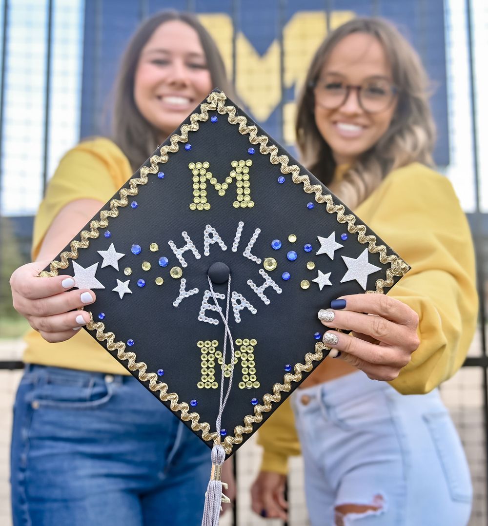 Decorated graduation cap with 'Hail Yeah' text and University of Michigan colors.