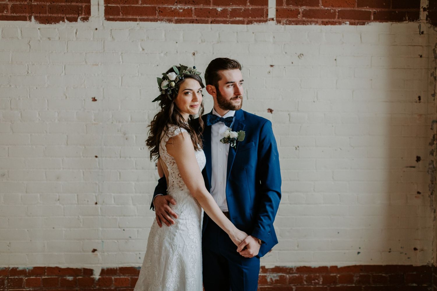 Modern wedding photography session against industrial brick and white wall backdrop.